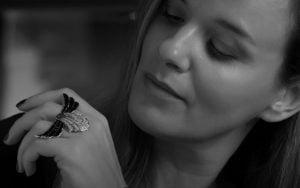 A woman wearing a striking statement ring with intricate design, showcasing elegance and style in a close-up view.