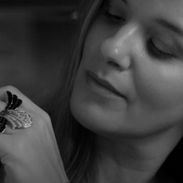 A woman wearing a striking statement ring with intricate design, showcasing elegance and style in a close-up view.