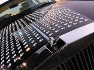 Luxury Rolls Royce car featuring a diamond-studded hood ornament and sparkling surface, showcasing opulence and elegance.