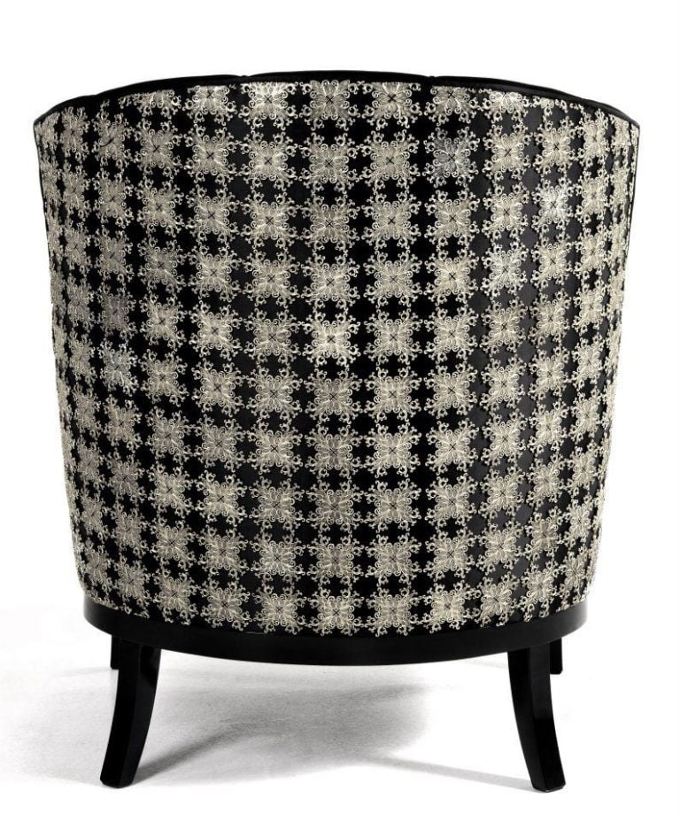 Upholstered chair featuring a black and white floral pattern on the back, with four wooden legs, showcasing intricate design elements.