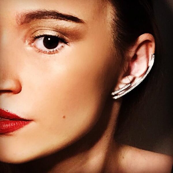 Close-up of a model showcasing elegant silver earrings, featuring a sleek design and sparkling details, with a focus on facial features.