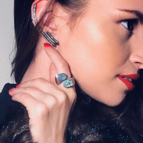 Close-up of a model showcasing a silver ear cuff and a matching ring with turquoise accents, highlighting modern jewelry design.