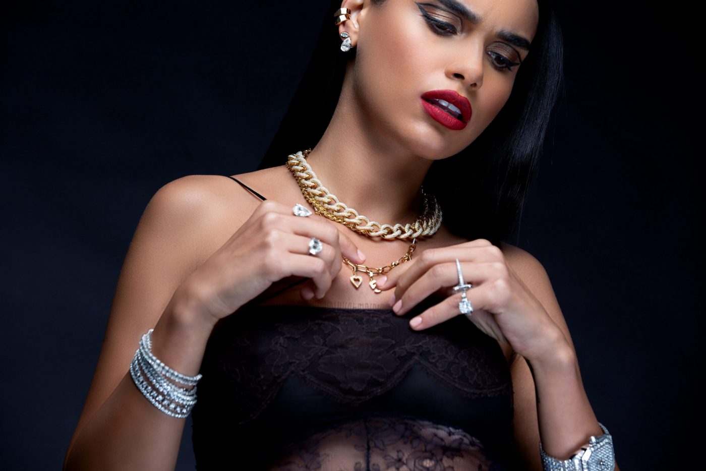 A model showcasing a variety of elegant jewelry including necklaces, rings, and bracelets against a dark background.
