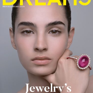 Close-up of a model showcasing a pink gemstone ring on her hand, featured on the cover of Dreams magazine, highlighting jewelry's free spirit.