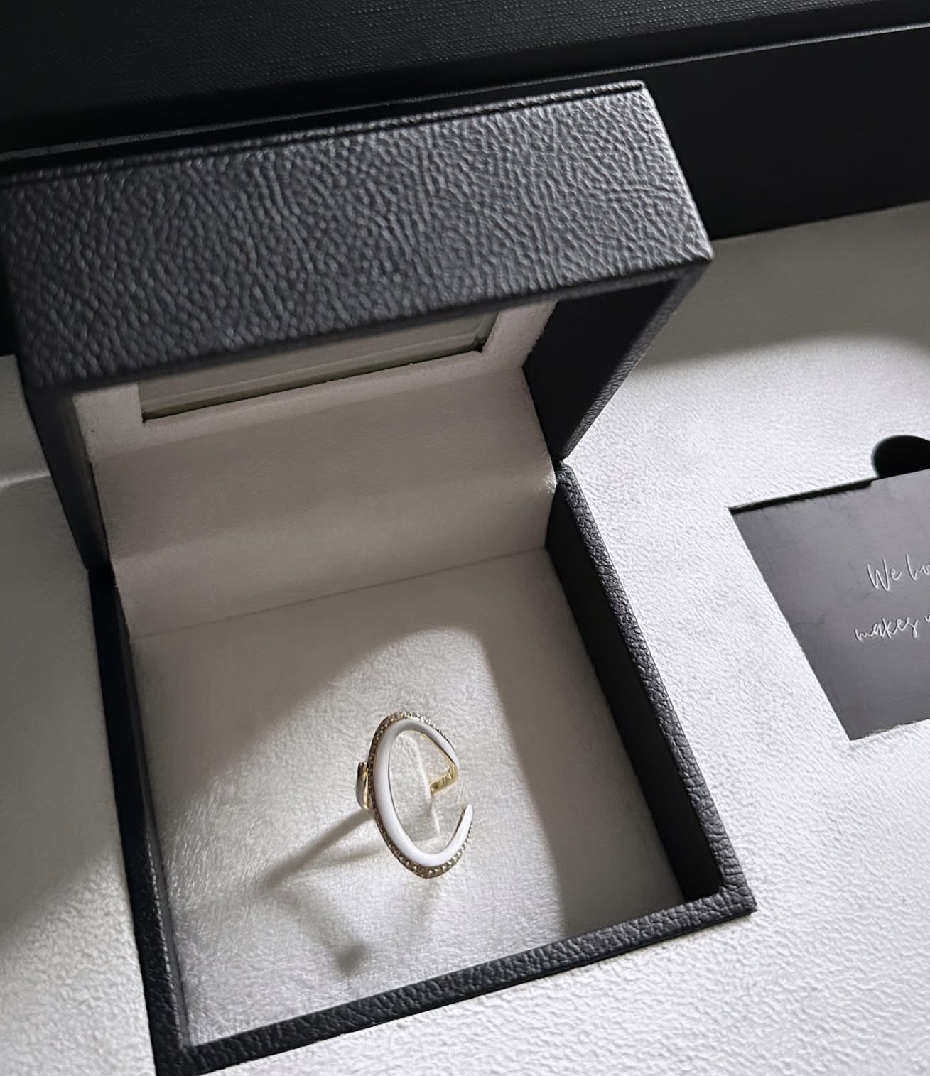 A silver ring with a unique design placed inside a black jewelry box with a soft interior lining.