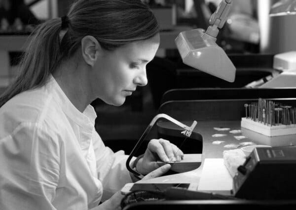 A focused jewelry artisan meticulously crafting a piece, showcasing precision and skill in a workshop environment.