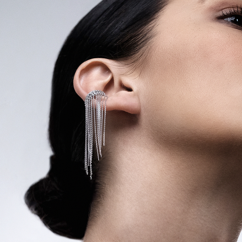 Close-up of a model wearing silver chain earrings that hang elegantly from the ear.