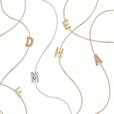 A collection of Letter Mania sautoir necklaces featuring gold, silver, and diamond-encrusted letters on delicate chains.