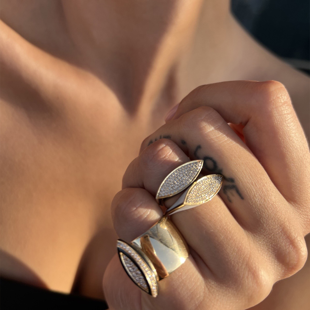 Close-up of a hand wearing multiple rings from the Maxi USTP Pave collection, featuring intricate designs and sparkling details.
