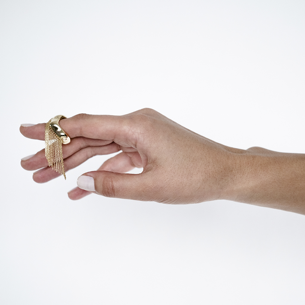 Elegant gold statement ring featuring fringe detail, showcased on a hand with a neutral background, highlighting its unique design.