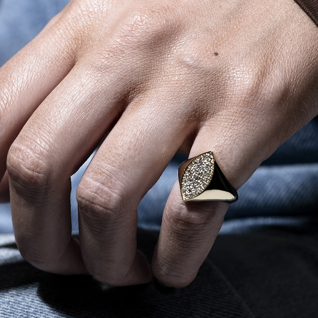 A hand wearing a geometric ring featuring sparkling details on a finger.