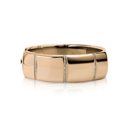 Gold bangle bracelet featuring diamond accents along the surface.