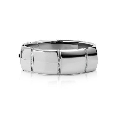 A polished silver bangle featuring diamond accents along its surface.