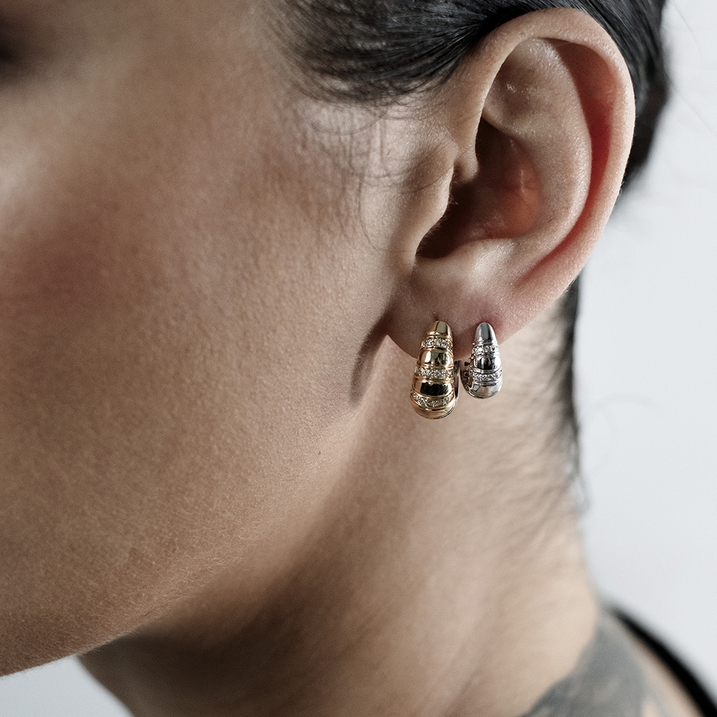 A person wearing gold and silver hoop earrings on their ear.