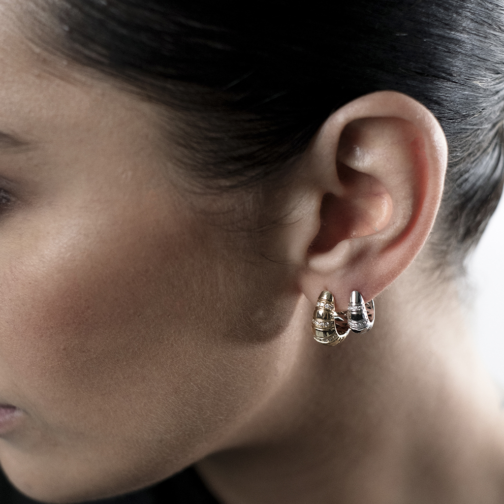 Close-up of a model wearing gold and silver hoop earrings in her ear.