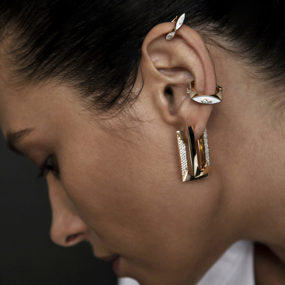 Close-up of a model wearing gold and silver earrings with a unique design.