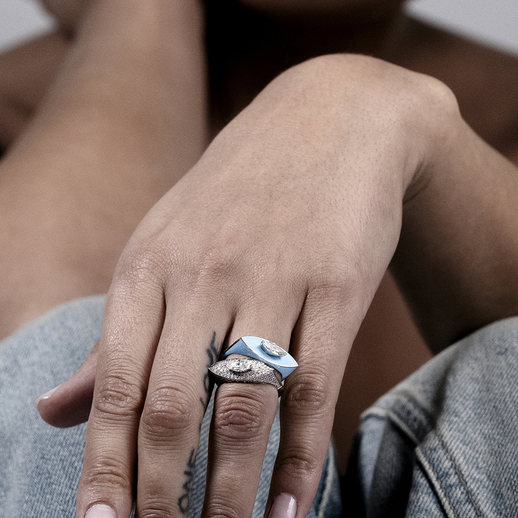 A close-up of a hand with a silver and blue ring on the finger, showcasing a unique design.