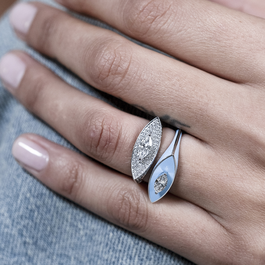 Two silver rings with diamonds displayed on a person's hand with light-colored nails.