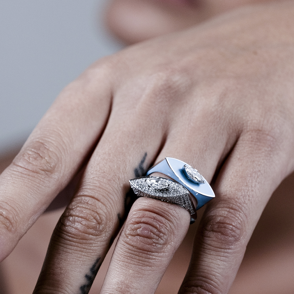 A hand wearing two distinct rings, one with a smooth surface and the other with a textured design.