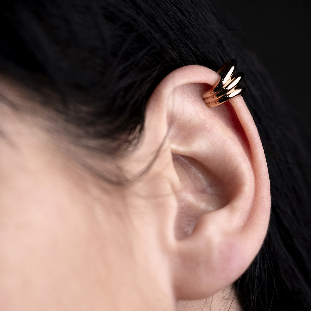 Close-up of a gold and black ear cuff worn on the upper part of an ear.