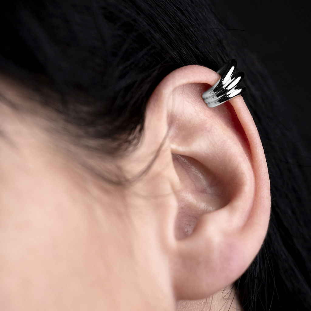 Close-up of a silver ear cuff worn on the upper part of a human ear.