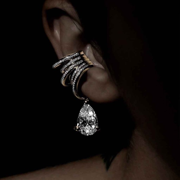 Gold ear cuff with diamond accents and a teardrop-shaped diamond pendant worn on the ear.